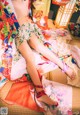 A woman in a colorful kimono laying on a bed.