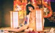 A naked woman in a kimono sitting on the floor next to a lamp.