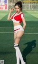 A woman in a red and white outfit on a soccer field.