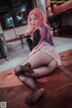 A woman with pink hair sitting on the floor.