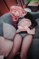 A woman with pink hair sitting on a couch.