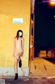 A naked woman wearing a face mask standing on a sidewalk.