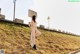 A naked woman leaning against a wall on the side of a road.