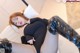 A woman in a black bodysuit and thigh high boots laying on a bed.