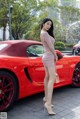 A woman standing next to a red sports car.