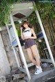 A woman standing in front of a phone booth talking on a cell phone.