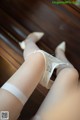 A woman wearing white stockings and high heels on a wooden floor.