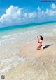 A woman in a red bikini sitting on the beach.