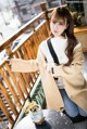 a woman sitting on a balcony wearing a beige coat