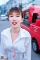 A woman in a white shirt standing in front of a red truck.