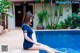 A woman in a blue dress sitting on the edge of a swimming pool.