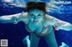 A woman in a bikini underwater making a peace sign.