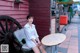 A woman sitting on a bench in front of a red building.