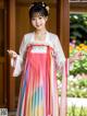 A woman in a pink and blue hanbok is posing for a picture.