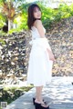 A woman in a white dress standing on a wooden dock.