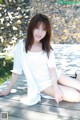 A woman in a white dress sitting on a wooden dock.