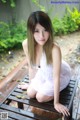 A woman in a white dress sitting on a wooden bench.