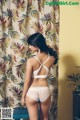 A woman in a white lingerie standing in front of a curtain.