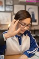 A woman wearing glasses sitting at a table with a book.