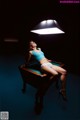 A woman sitting on top of a pool table under a light.