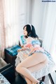 A woman sitting on top of a bed next to a window.