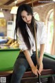 A woman sitting on top of a pool table holding a cue.