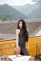 A woman in a black dress standing on a wooden deck.