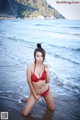 A woman in a red bikini sitting in the water.