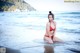 A woman in a red bikini sitting in the water.