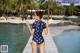 A woman in a blue and white polka dot swimsuit standing on a dock.