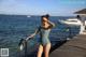 A woman in a bathing suit standing on a dock by the water.