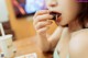 A woman sitting at a table eating a piece of food.