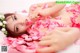 A woman laying on a bed of pink rose petals.