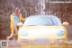 A woman standing next to a yellow sports car.