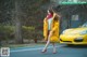 A woman in a yellow coat is walking by a yellow car.