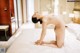 A naked woman sitting on a bed in a hotel room.