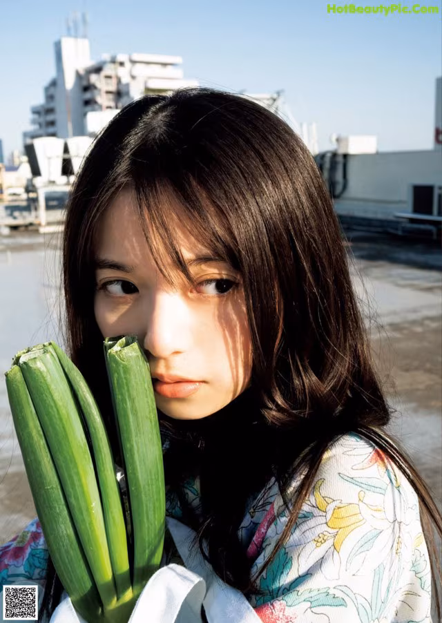 A woman holding a bunch of green onions in her hand.