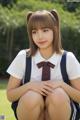 A young woman in a school uniform sitting on the grass.