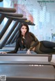 A woman laying on a treadmill in a gym.