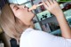 A woman in a white shirt is holding a wooden stick in her mouth.