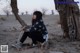 A woman sitting on the ground next to a tree.