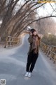 A woman standing on the side of a road with trees in the background.