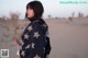 A woman standing in the middle of a desert.