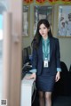 A woman in a business suit standing in front of a computer.