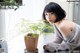 A woman sitting at a table next to a potted plant.