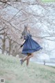 A woman in a blue dress is standing in the grass.