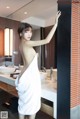 A woman in a white towel standing in a bathroom.