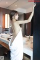 A woman in a white towel standing in front of a mirror.