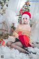 A woman sitting on the ground in front of a Christmas tree.