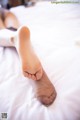 A woman laying on a bed with her feet up.